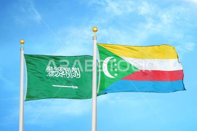 Saudi Arabia and Comoros two flags on flagpoles and blue cloudy sky