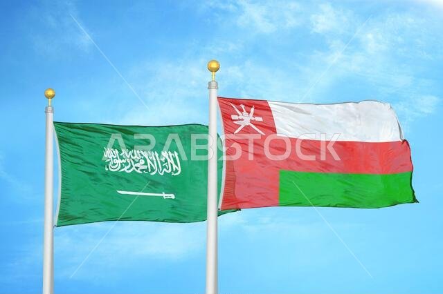 Saudi Arabia and Oman two flags on flagpoles and blue cloudy sky