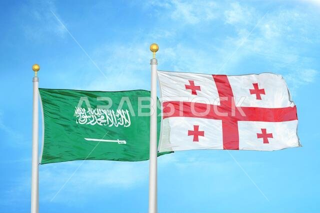 Saudi Arabia and Georgia two flags on flagpoles and blue cloudy sky