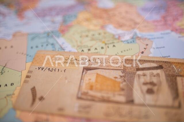 Ten riyals bill below Saudi Arabia on a colorful and blurry map of Western Asia