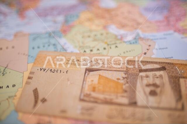 Ten riyals bill below Saudi Arabia on a colorful and blurry map of Western Asia