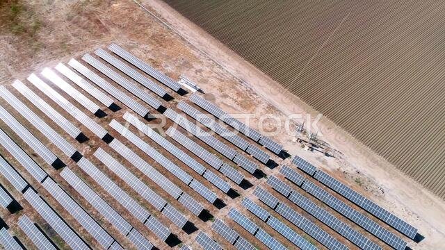 aerial view of solar energy panels and plowed agriculture field