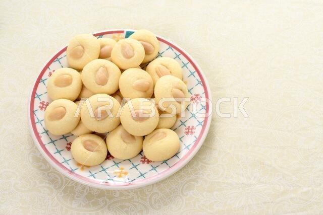 Graibe a buttery Arab biscuit with an almond on a plate