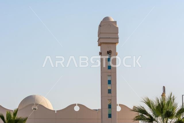 A common small mosque minaret. with palm tree in the corniche coastal park in Dammam, Kingdom of Saudi Arabia