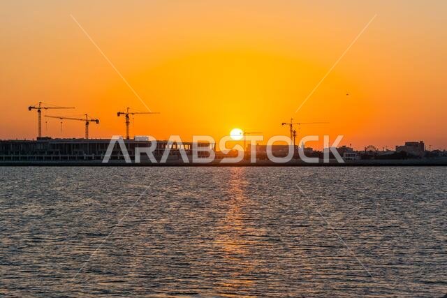 Landscape of sun rising over the construction site with crane in the sea in the morning in Dammam, Kingdom of Saudi Arabia