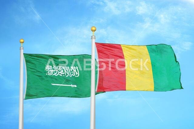 السعودية وغينيا، علمان على سارية علم، وسماء زرقاء ملبدة بالغيوم