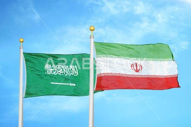 السعودية وإيران، علمان على سارية علم، وسماء زرقاء ملبدة بالغيوم