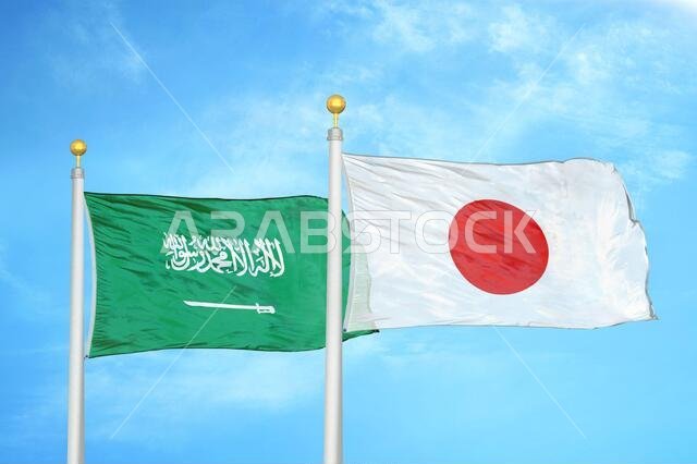 Saudi Arabia and Japan two flags on flagpoles and blue cloudy sky