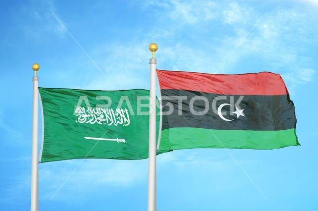 Saudi Arabia and Libya two flags on flagpoles and blue cloudy sky
