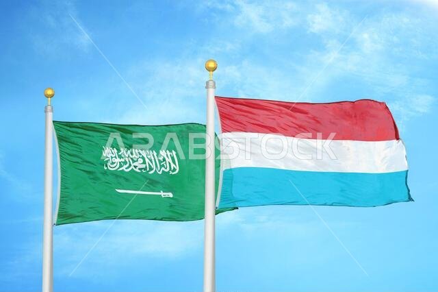 Saudi Arabia and Luxembourg two flags on flagpoles and blue cloudy sky