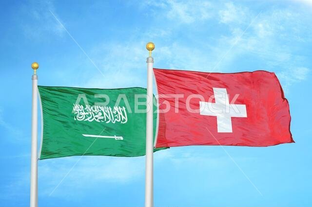 Saudi Arabia and Switzerland two flags on flagpoles and blue cloudy sky Saudi Arabia and Switzerland two flags on flagpoles and blue cloudy sky