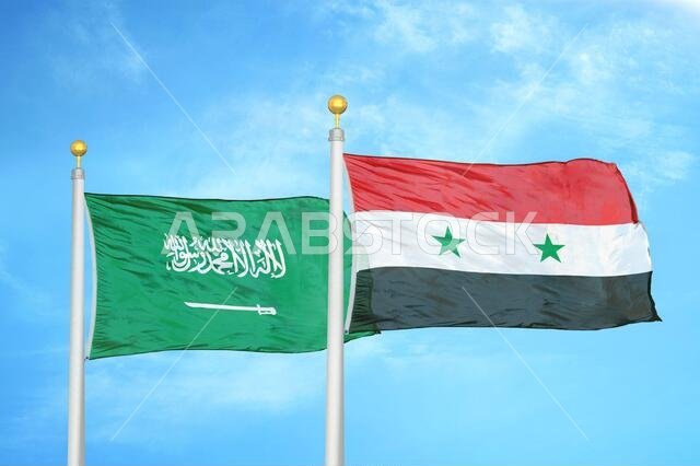 Saudi Arabia and Syria two flags on flagpoles and blue cloudy sky