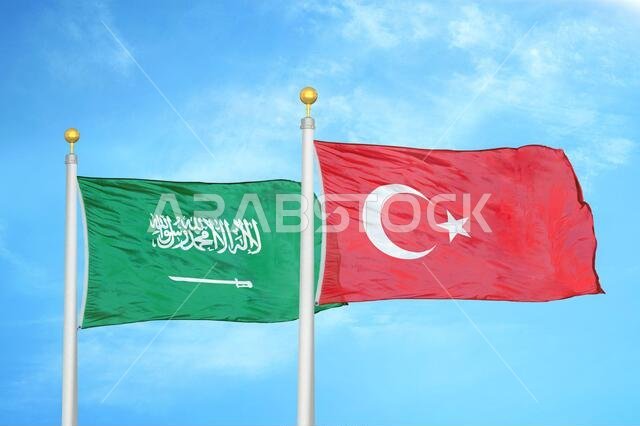 Saudi Arabia and Turkey two flags on flagpoles and blue cloudy sky