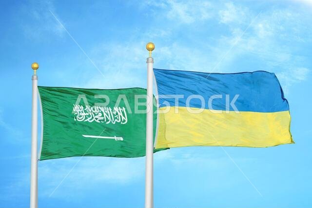 Saudi Arabia and Ukraine two flags on flagpoles and blue cloudy sky