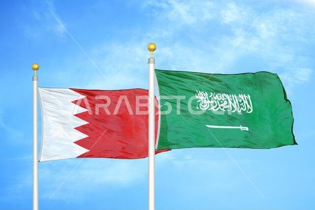 Bahrain and Saudi Arabia two flags on flagpoles and blue sky