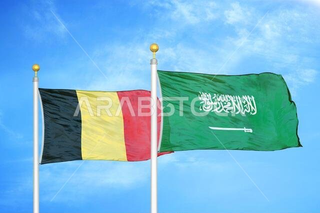 Belgium and Saudi Arabia two flags on flagpoles and blue cloudy sky