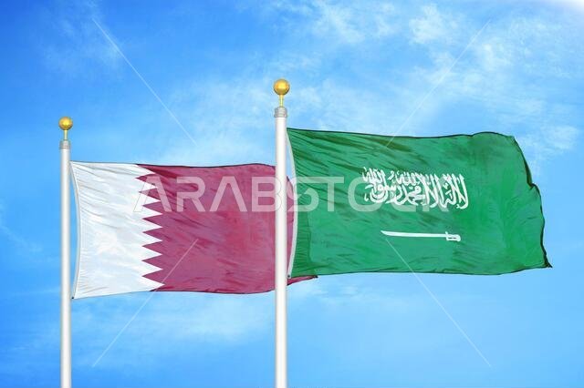 Qatar and Saudi Arabia two flags on flagpoles and blue cloudy sky
