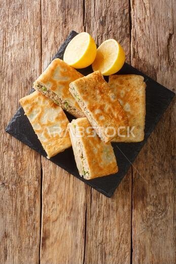 Mutabbaq is a delicious stuffed paratha with spicy minced meat, which is a popular street food in Saudia Arabia closeup in the board on the table. ver