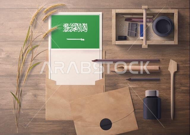Saudi Arabia invitation, celebration letter concept. Flag with craft paper and envelope. Retro theme with divide, ink, wooden pen objects.