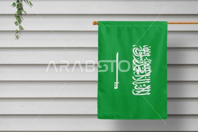 Saudi Arabia national small flag hangs from a picket fence along the wooden wall in a rural town. Independence day concept.