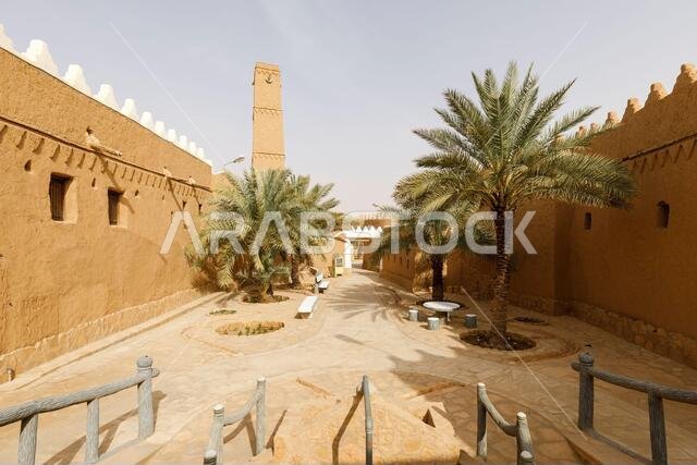 Alley with palm trees and renovated houses in the traditional village of Shaqra in Saudi Arabia. Shaqra is a traditional restored village made of clay