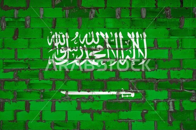 العلم الوطني للمملكة العربية السعودية مرسوم على جدار من الطوب الإسمنتي. رمز الدولة.