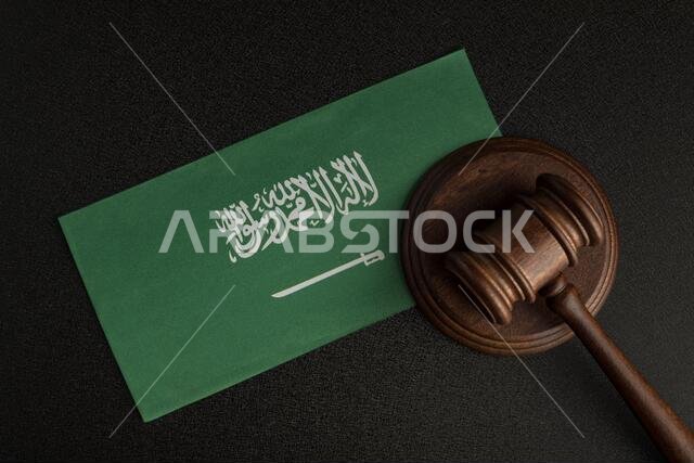 رمز العدالة بمطرقة خشبية على علم المملكة العربية السعودية. مكتبة قانونية. مفهوم القانون والعدالة.