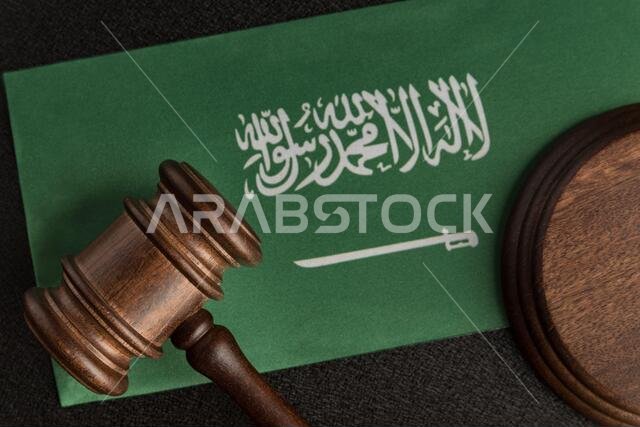 رمز العدالة بمطرقة خشبية على علم المملكة العربية السعودية. مكتبة قانونية. مفهوم القانون والعدالة.