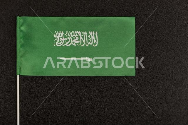 Table flag of Kingdom of Saudi Arabia on black background. Green flag with sword