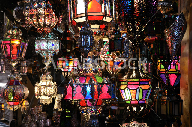 صورة مقربة لفوانيس رمضانية بأشكال وألوان مختلفة للإضاءة  , محل متخصص لبيع الإنارة , ثريا معلقة على السقف , أضواء خافتة . 