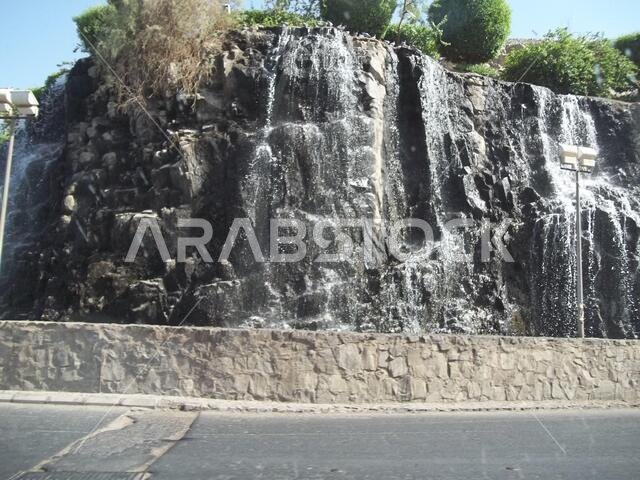 منظر من الطريق لشلال نبع طبيعي على جانب جبل في المملكة العربية السعودية