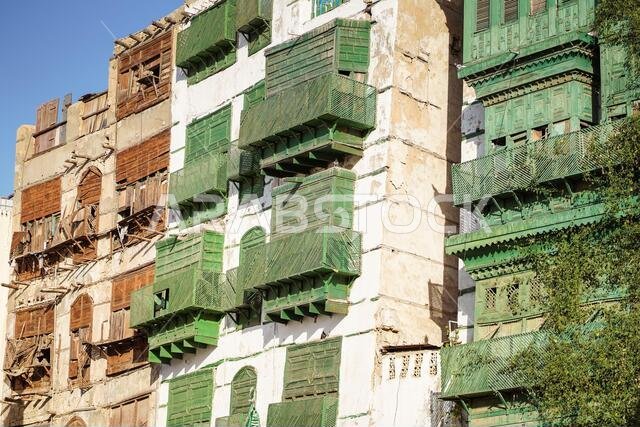 زاوية منخفضة لمبانٍ حجرية قديمة ذات جدران وشرفات متداعية في أحد شوارع مدينة جدة بالمملكة العربية السعودية