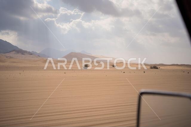Scenic landscape of sun rays through clouds in desert from car window in Saudi Arabia