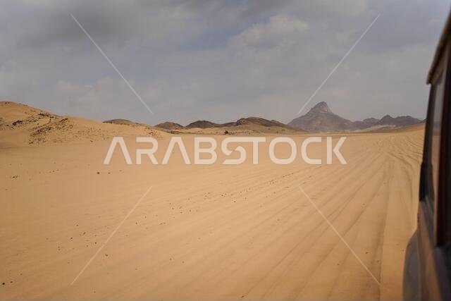 Scenic landscape of sun rays through clouds in desert from car window in Saudi Arabia
