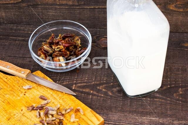 Hushaf - date milk, traditional ramadan dish, cooking, ingredients, pitted dates in a plate, knife and seeds on a cutting board and milk in the bottle