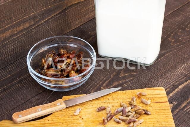 Hushaf - date milk, traditional ramadan dish, cooking, ingredients, pitted dates in a plate, knife and seeds on a cutting board and milk in the bottle