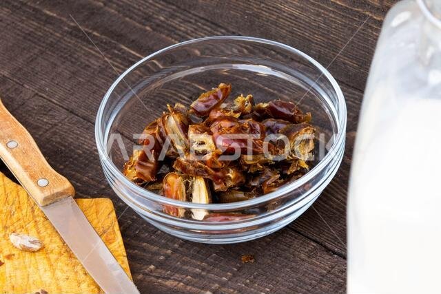 حمص - حليب التمر، طبق رمضاني تقليدي، طريقة التحضير، المكونات، تمر منزوع النوى في طبق، سكين وبذور على لوح تقطيع، والحليب في زجاجة