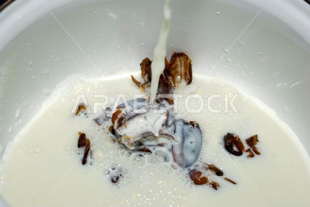 Hushaf - date milk, a traditional dish of Ramadan, cooking, ingredients, seedless dates lying in the saucepan pouring a stream of milk Hushaf - date milk, a traditional dish of Ramadan, cooking, ingredients, seedless dates lying in the saucepan pouring a stream of milk