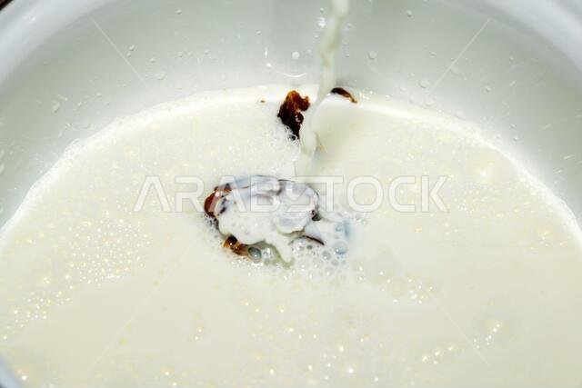 Hushaf - date milk, a traditional dish of Ramadan, cooking, ingredients, seedless dates lying in the saucepan pouring a stream of milk Hushaf - date milk, a traditional dish of Ramadan, cooking, ingredients, seedless dates lying in the saucepan pouring a stream of milk
