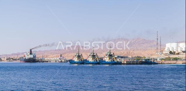 Tug boats and cargo ships are moored in Aqaba Port at sunny day, Jordan