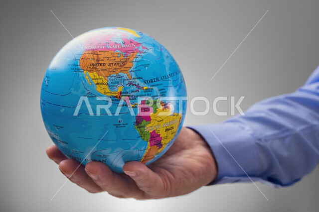 صورة مقربة لرجل يحمل بيده مجسم الكرة الأرضية ، خريطة العالم ، البلدان والقارات ، كرة أرضية ملونة