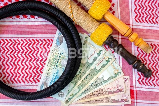 العملات العربية: الدرهم الإماراتي، الأوراق النقدية، النرجيلة، والملابس العربية التقليدية للرجال - صورة مقربة للكوفية والعقال.