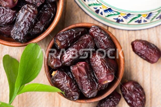 Dried dates in bowl on wooden table background, top view. Islamic Arabic food concept