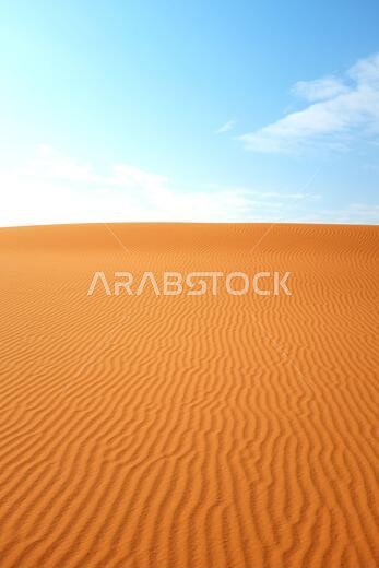 تموجات رمال الصحراء البرتقالية الزاهية وسماء زرقاء صافية لخلفية صيفية دافئة.