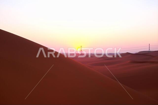 شروق الشمس بألوان الباستيل على الكثبان الرملية الحمراء لصحراء الدهناء في الرياض، المملكة العربية السعودية. بدايات جديدة، رمز للأمل ومستقبل أكثر إشراقاً.