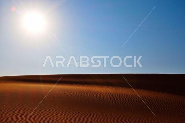 سماء زرقاء صافية في الصباح ورمال صحراوية متموجة في صحراء الدهناء، الرياض، المملكة العربية السعودية.