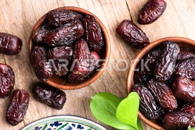 تمر مجفف في وعاء على خلفية طاولة خشبية. طعام عربي نباتي.