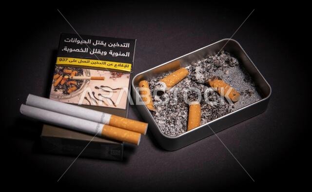 سجائر مع منفضة سجائر، مكتوب على العلبة: "التدخين يقتل الحيوانات المنوية ويقلل الخصوبة. للإقلاع عن التدخين، اتصل على 937". جدة، المملكة العربية السعودية، 2020
