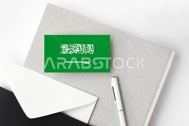 علم المملكة العربية السعودية على خلفية حروف بسيطة. ظرف دعوة وطنية مع قلم أبيض ودفتر ملاحظات. مفهوم التواصل.