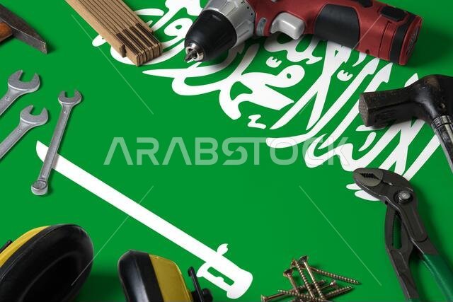 علم المملكة العربية السعودية موضوع على خلفية طاولة خشبية لأدوات الإصلاح. تصميم خدمة ميكانيكية مع رموز وطنية.